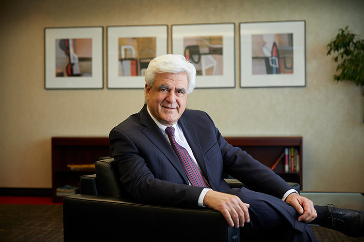 Portrait of a man in a suit relaxing in a chair.